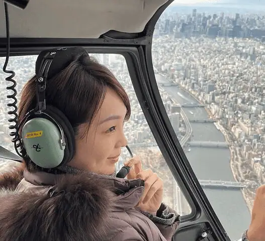 Helicopter soaring over Tokyo skyline with Mount Fuji in the distance.