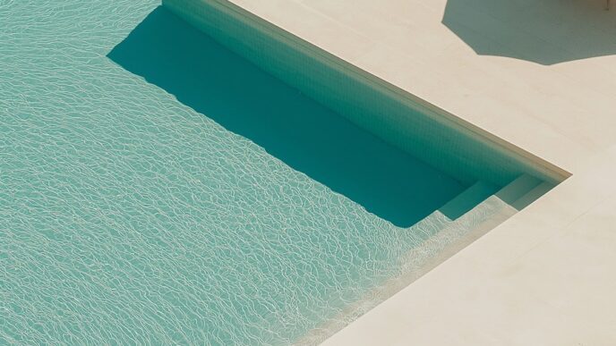 a pool with lounge chairs and a step