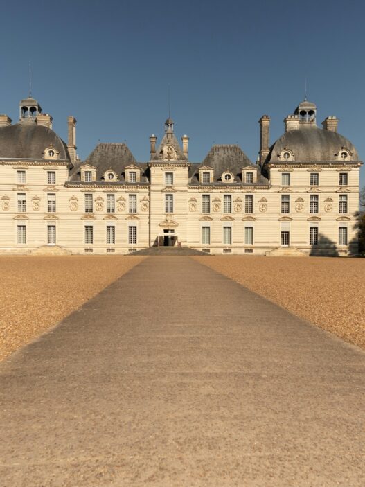 a large white building with a path leading to it with Château de Cheverny in the background