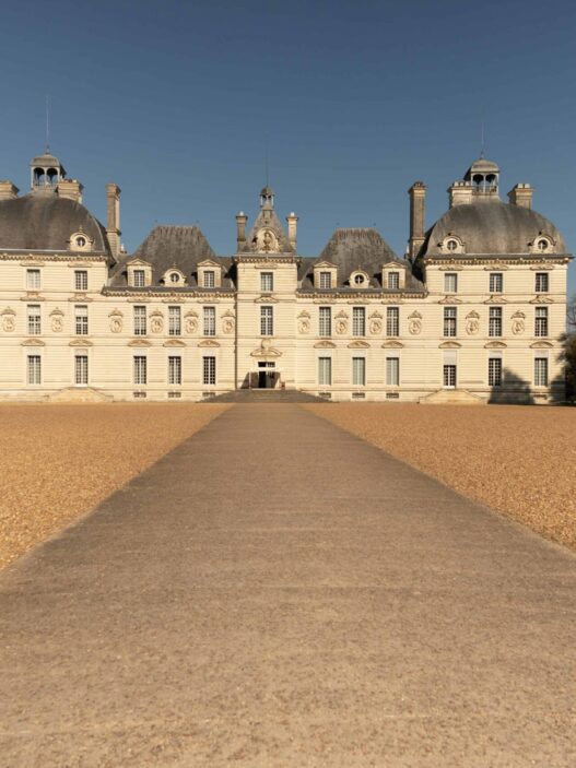 a large white building with a path leading to it with Château de Cheverny in the background