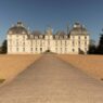 a large white building with a path leading to it with Château de Cheverny in the background