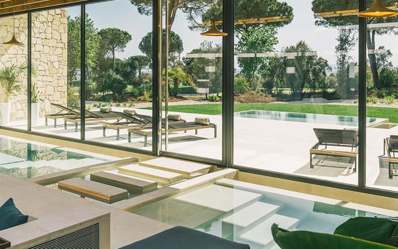 Luxury wellness retreats 2025 - Camiral Wellness Centre holistic spa with floor-to-ceiling windows, modern relaxation pools, natural stone walls, and Mediterranean garden views for integrated healing programs