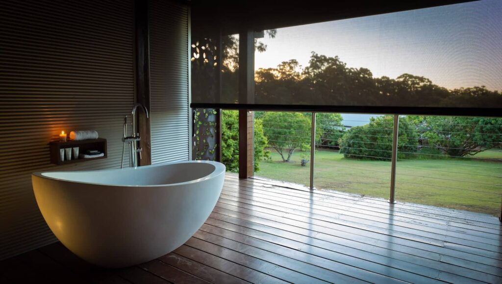 Luxury wellness retreats 2025 - Gwinganna Lifestyle Retreat modern bathroom with freestanding bathtub, floor-to-ceiling windows overlooking natural landscape, and warm lighting for digital detox excellence programs